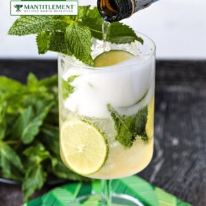 picture of champagne being poured into glass with mint and limes