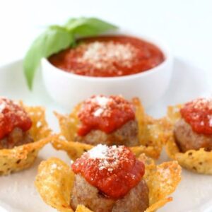 meatballs in a cheese crisp cup with sauce in background