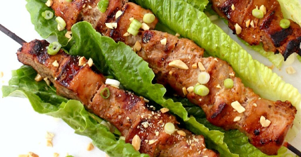 coconut pork kabobs in lettuce leaves with chopped peanut garnish