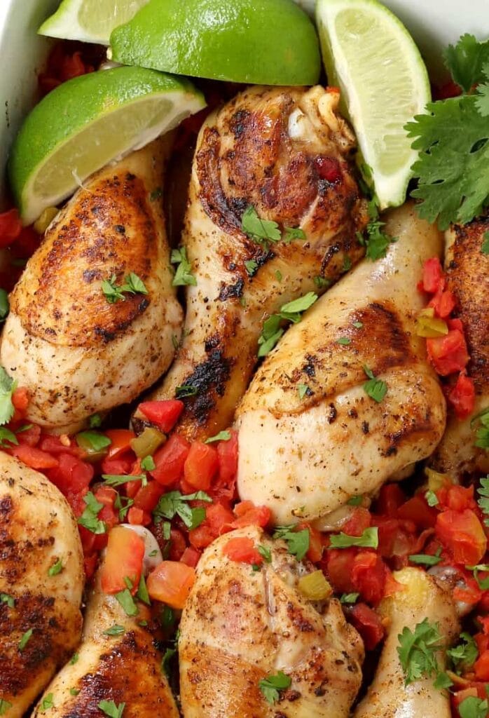 Oven Baked Fiesta Chicken Legs in a dish with limes