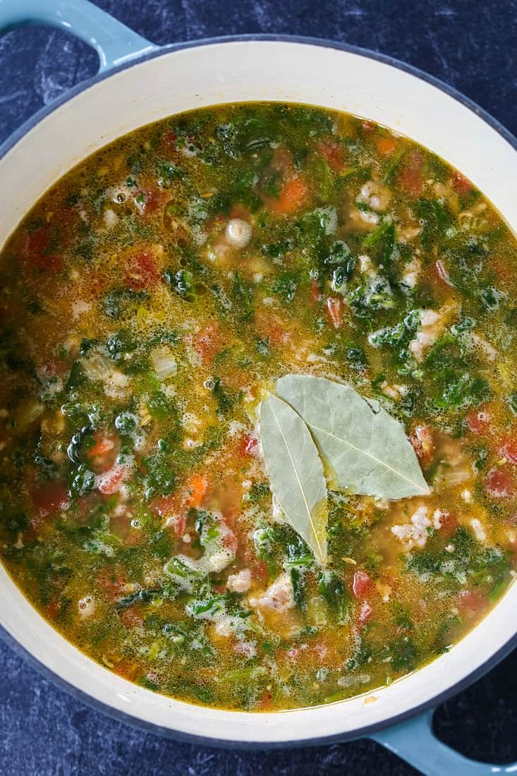 sausage and farro soup with spinach simmering in pot