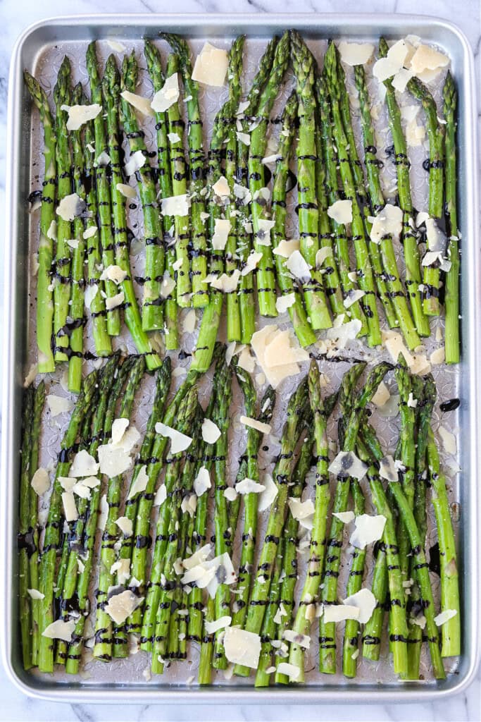 asparagus with parmesan cheese and balsamic glaze on a sheet pan