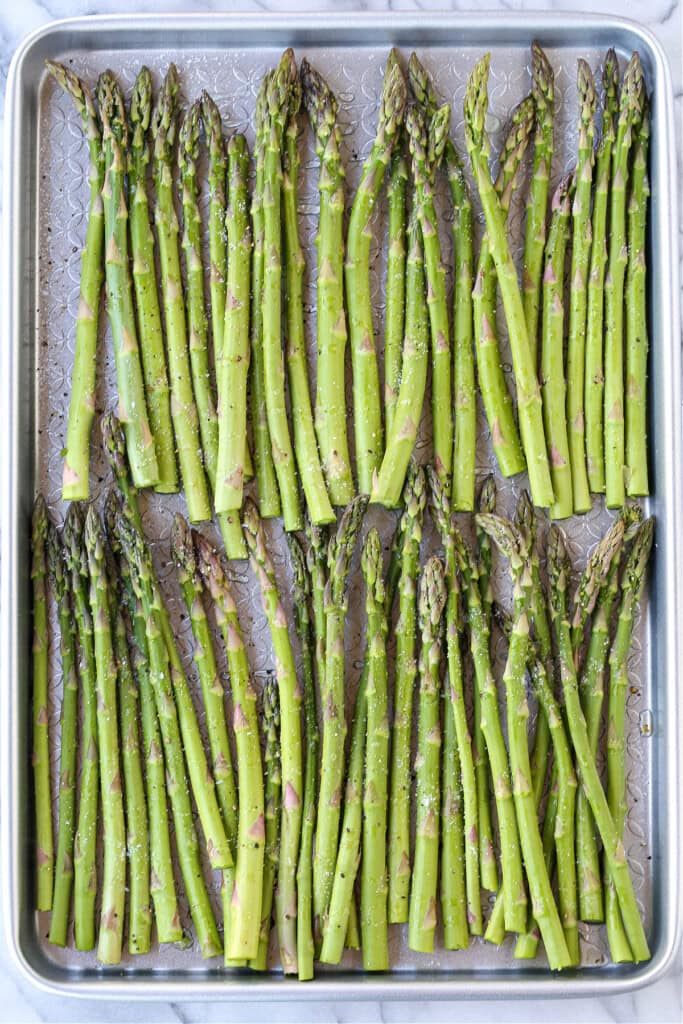 asparagus stalks on sheet pan with salt and pepper