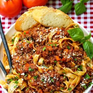 bolognese sauce over pasta on a red and white checkered tablecloth