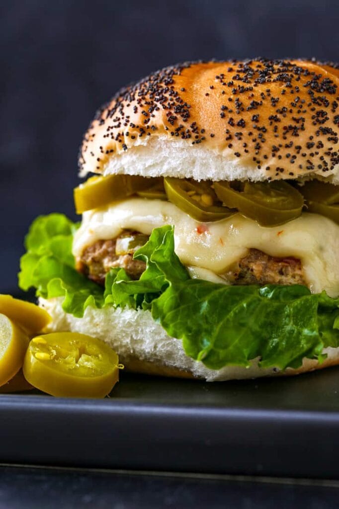 Turkey burger recipe with lettuce, cheese and jalapeños on a poppy seed bun
