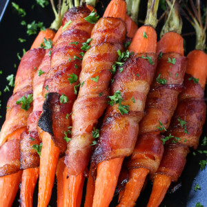 roasted carrots wrapped in bacon on black dish