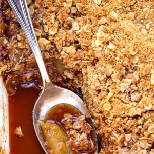 apple crisp in a baking dish with spoon and sauce