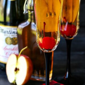 Apple cider cocktails with cherries and sparkling cider bottle