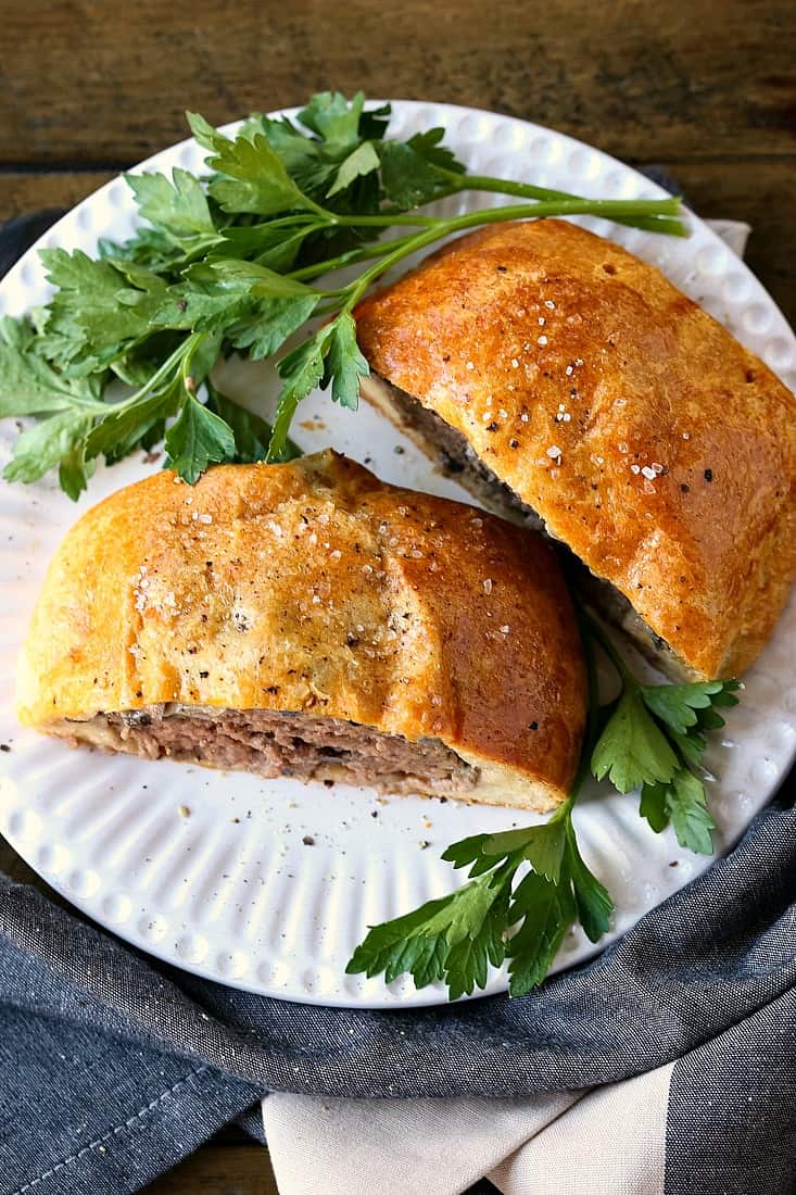 Individual Beef Wellington on white plate with parsley