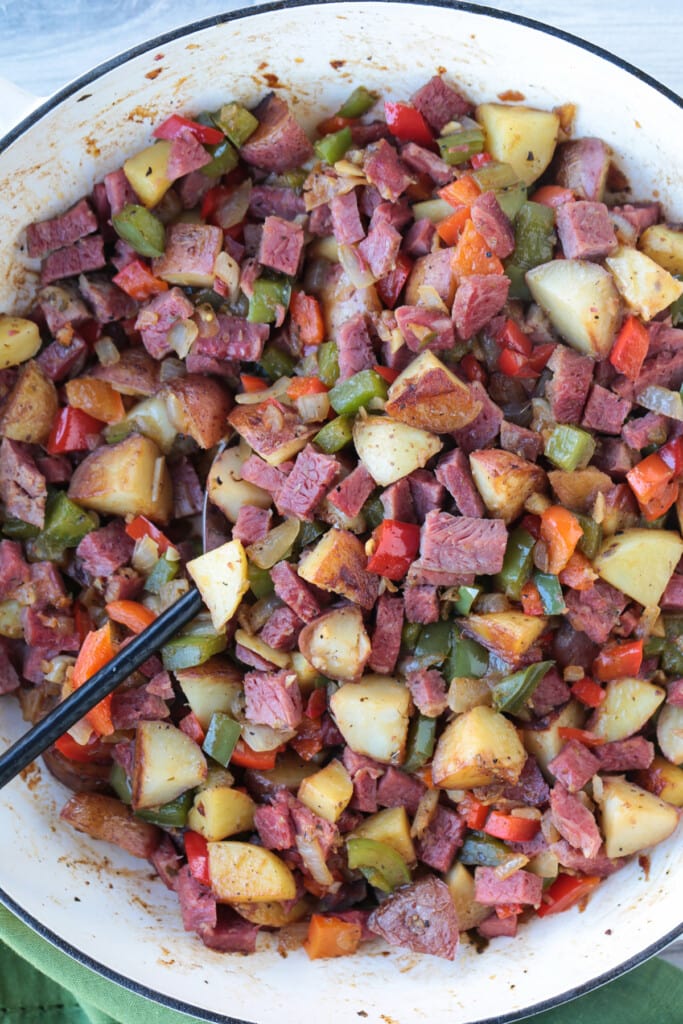 corned beef hash in skillet with serving spoon