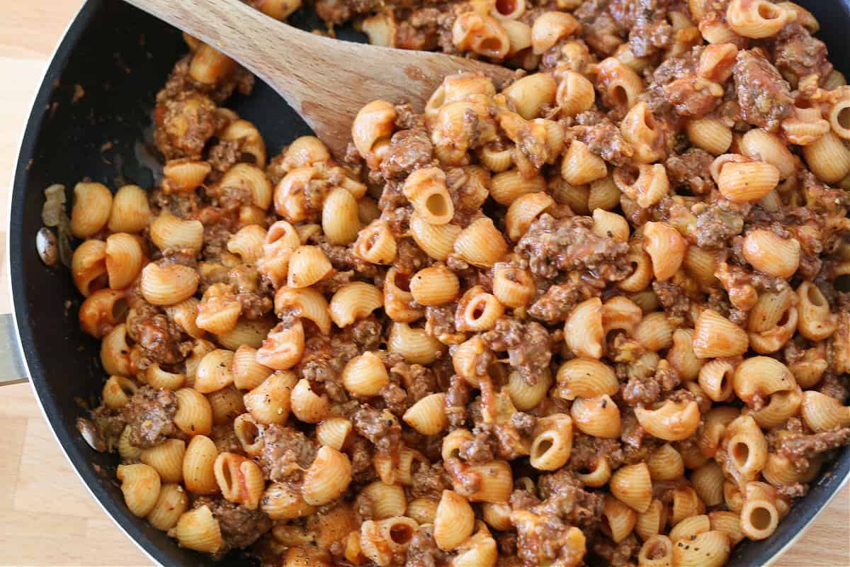 pasta mixed with sauce, ground beef and cheese in a skillet