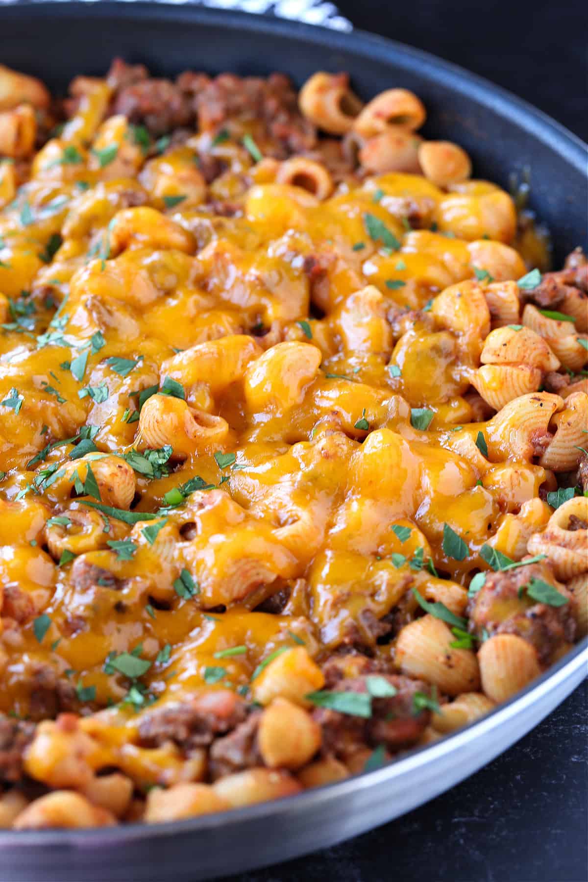 pasta with ground beef topped with cheese in skillet