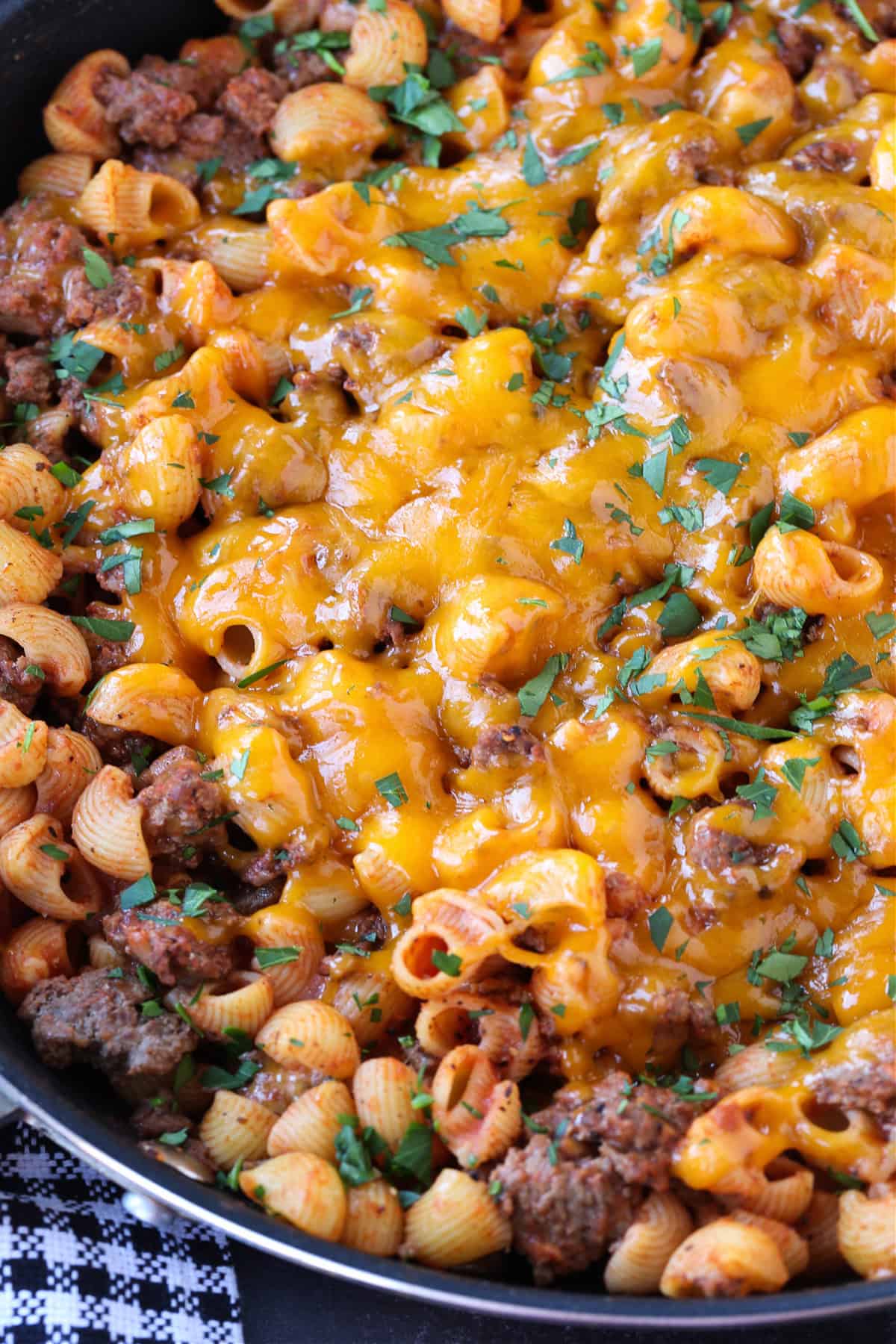 pasta and ground beef dinner topped with cheddar cheese in skillet