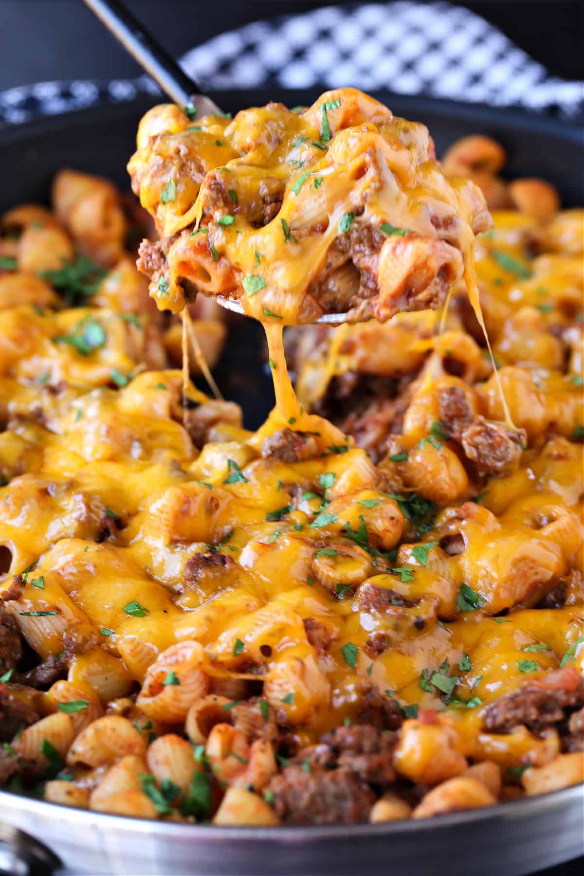 cheeseburger pasta in skillet with scoop on serving spoon