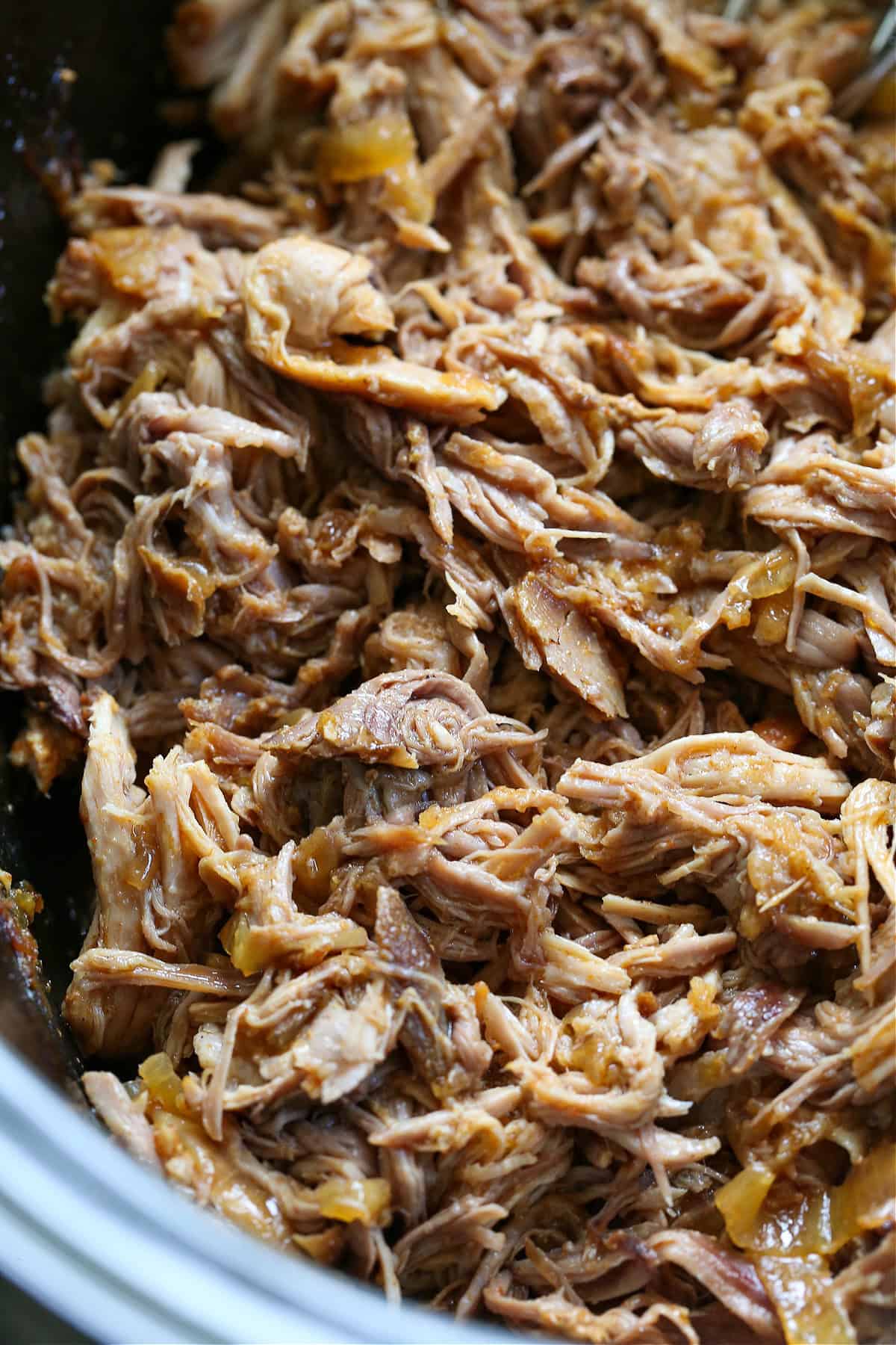 close up of pulled pork with onions in slow cooker