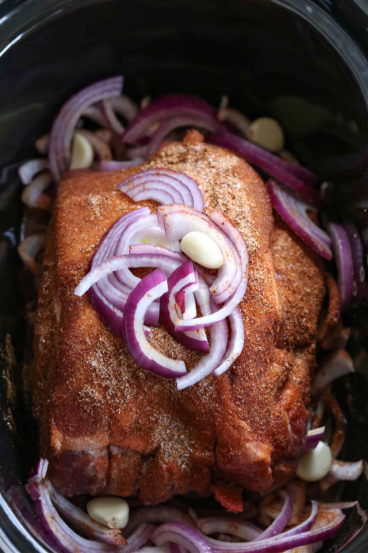 seasoned pork butt in slow cooker with onions