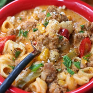 Soup recipe with sausage and pasta in a bowl with spoon