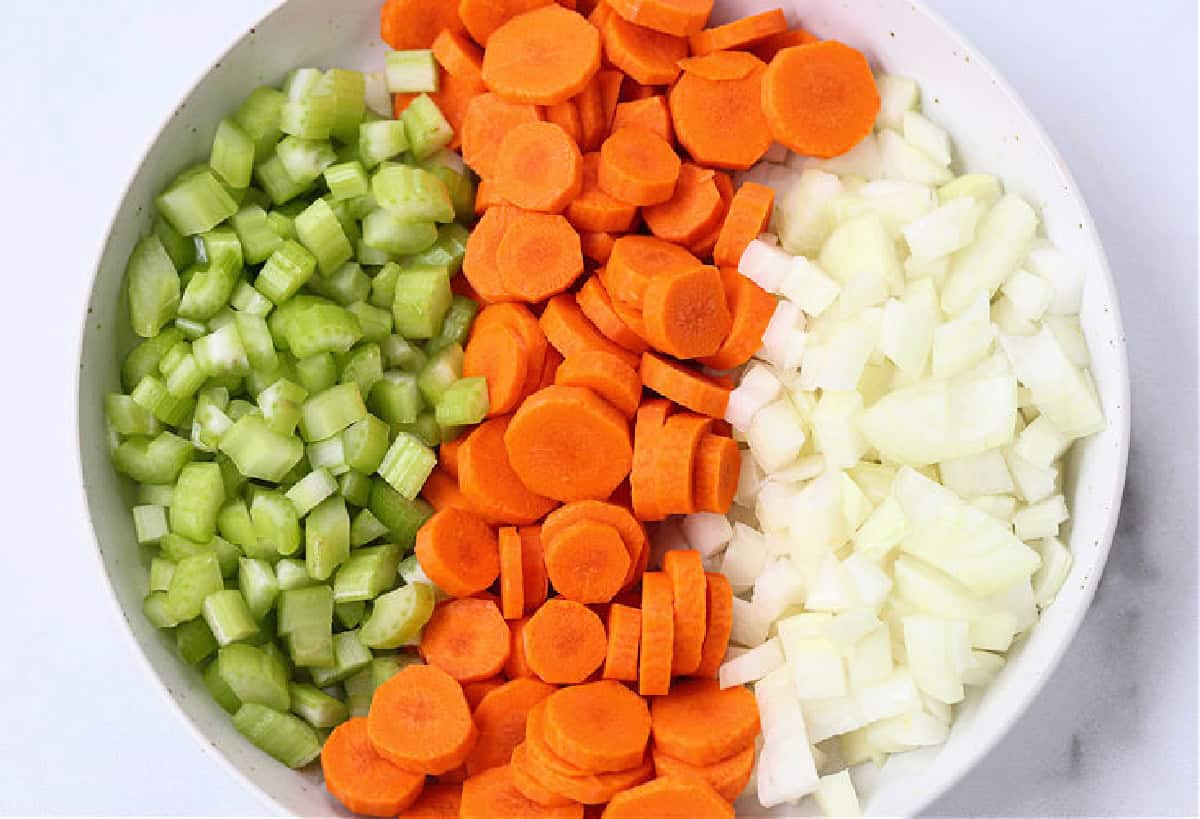 celery, carrots and onions on white plate for making soup