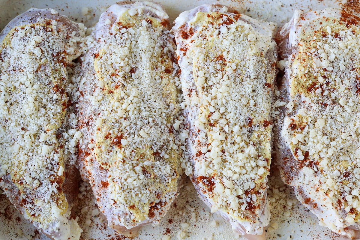 chicken breasts in baking dish with mayonnaise and parmesan cheese