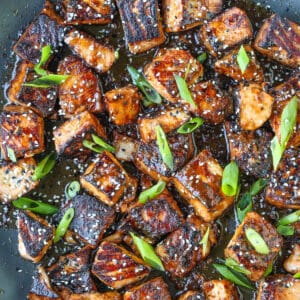 salmon bites in a skillet with scallions and sesame seeds