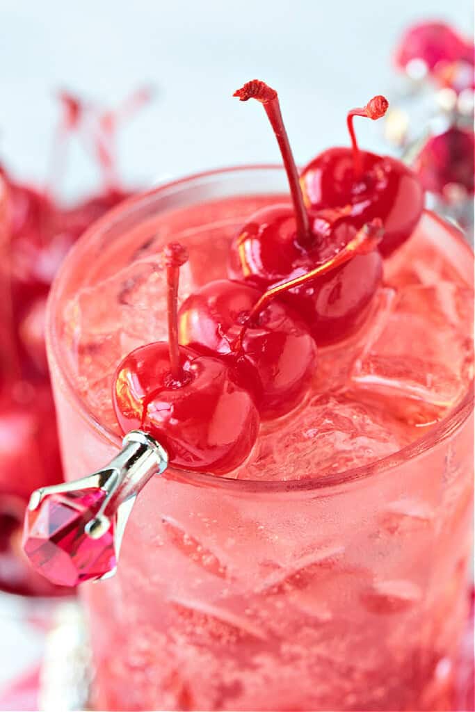 pink vodka cocktail garnished with maraschino cherries
