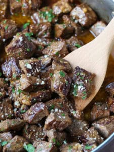 steak bites in garlic butter sauce with wooden spoon