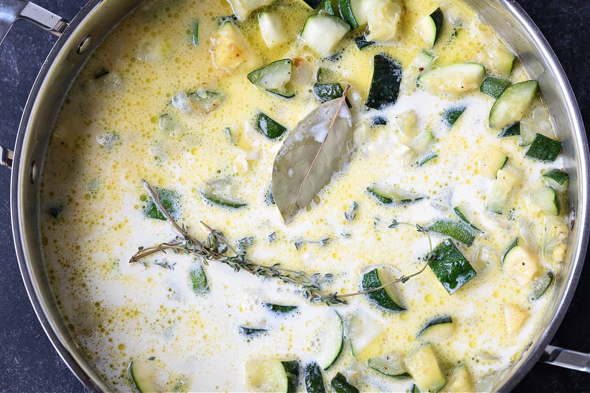 Cream, herbs and zucchini in a skillet for making homemade sauce