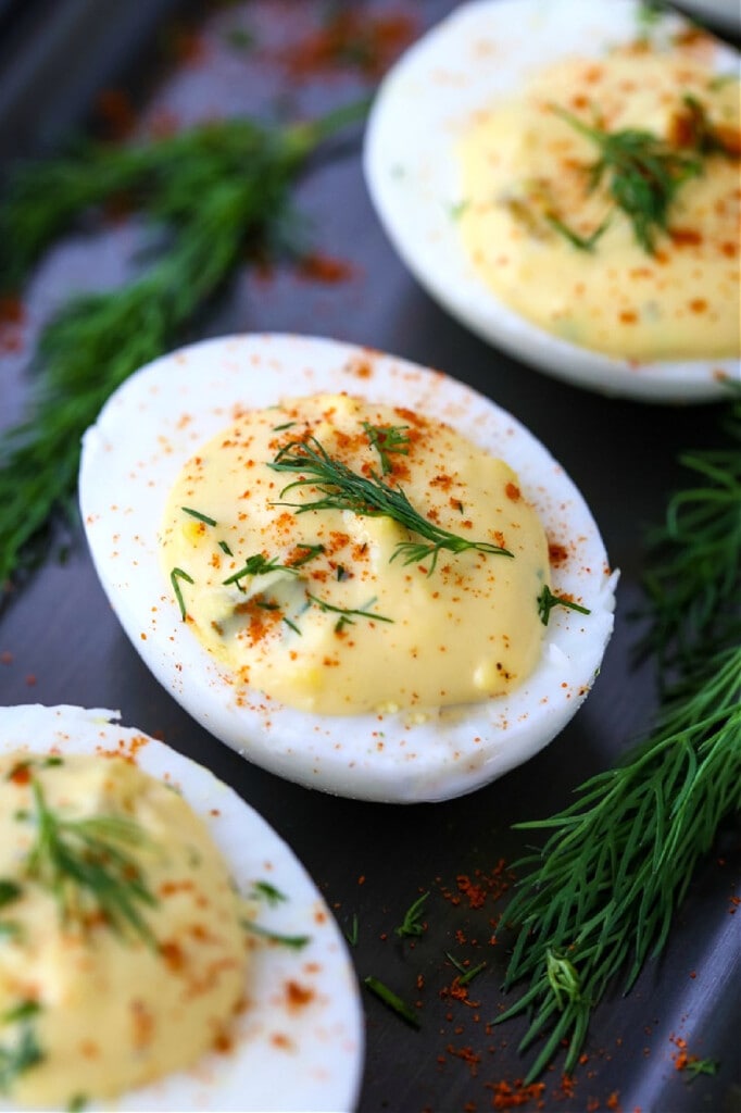 deviled eggs on a platter with fresh dill on top