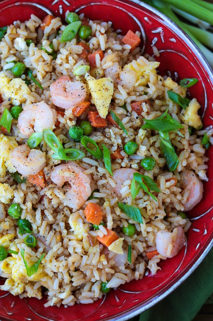 fried rice with shrimp in a red bowl with scallions for garnish