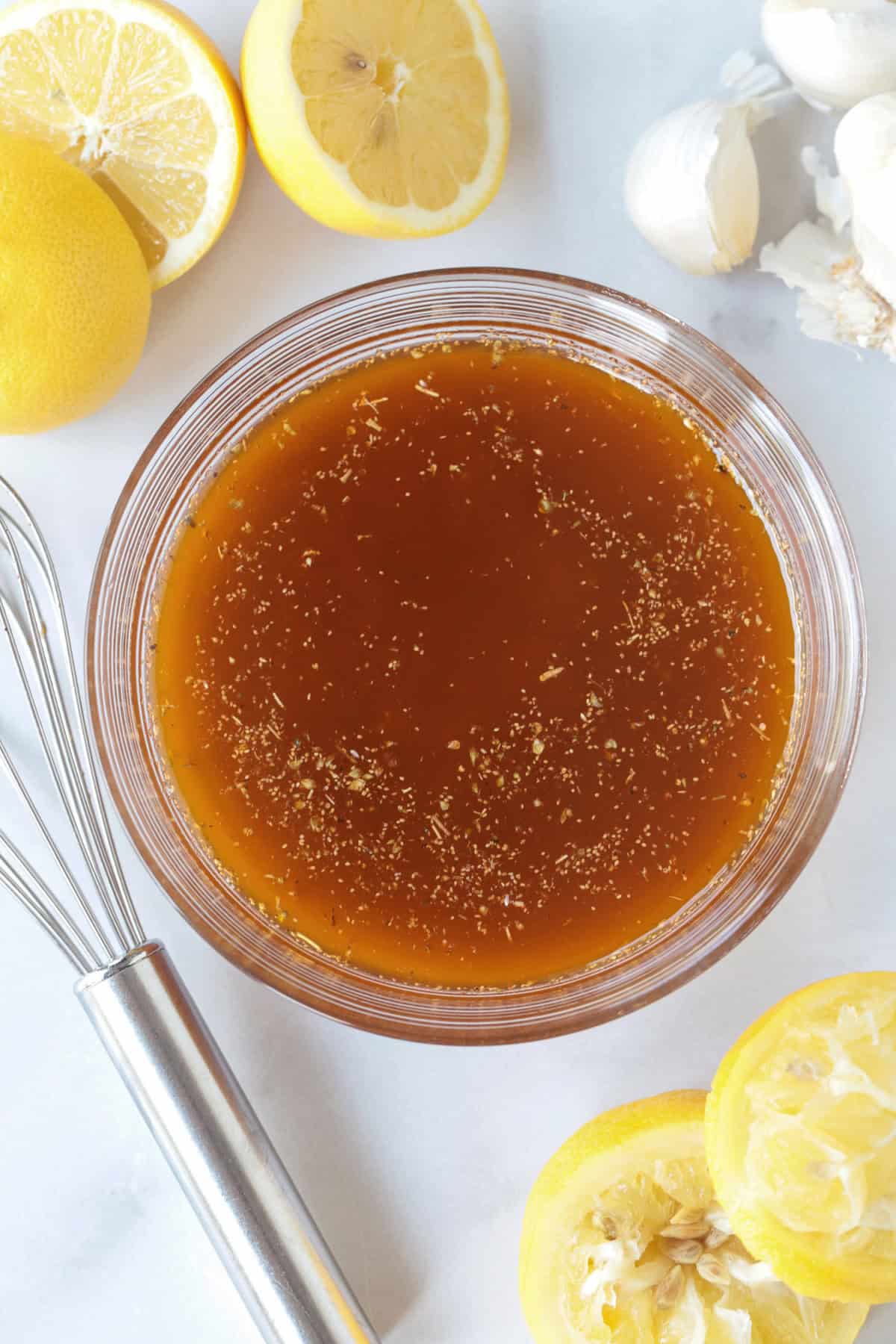 greek marinade in bowl with lemons and whisk