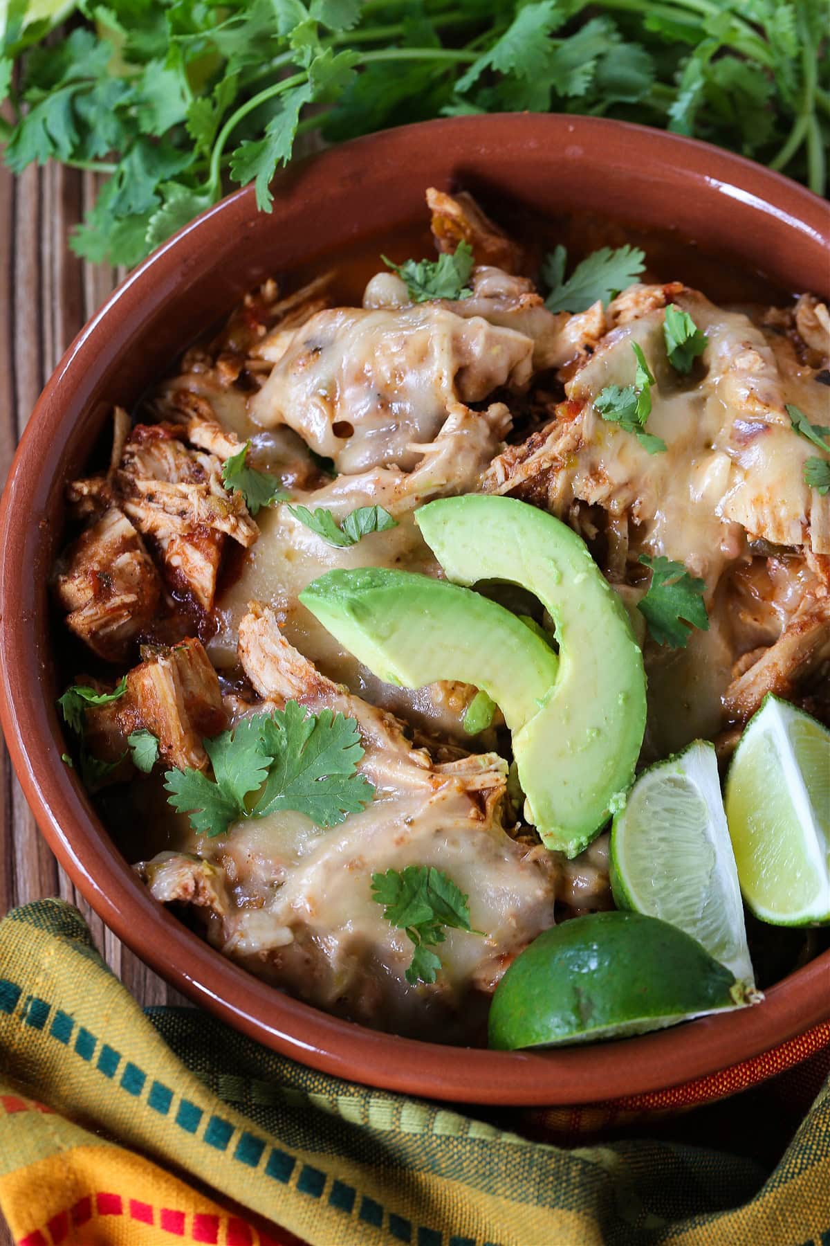 taco chicken in a bowl with sliced avocado and limes