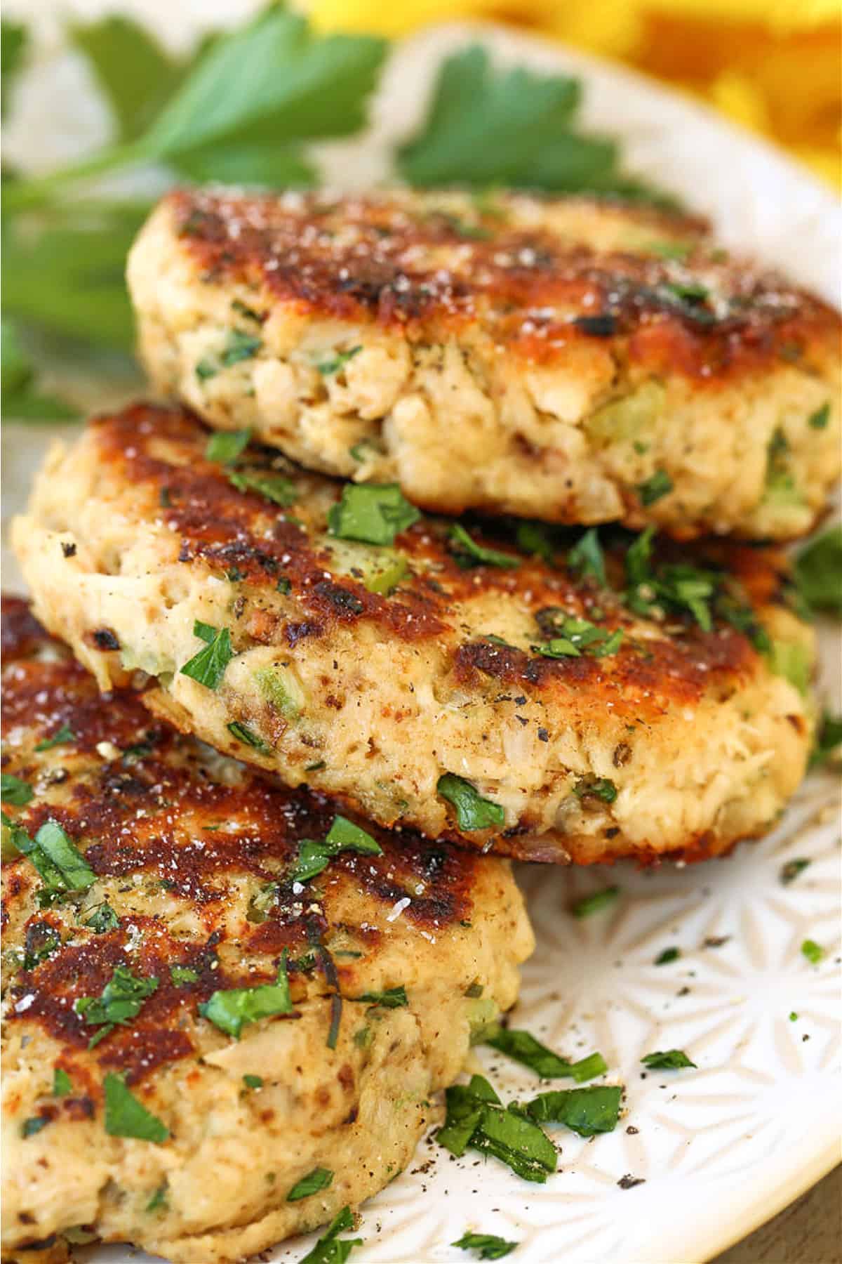 tuna cakes stacked on plate with parsley