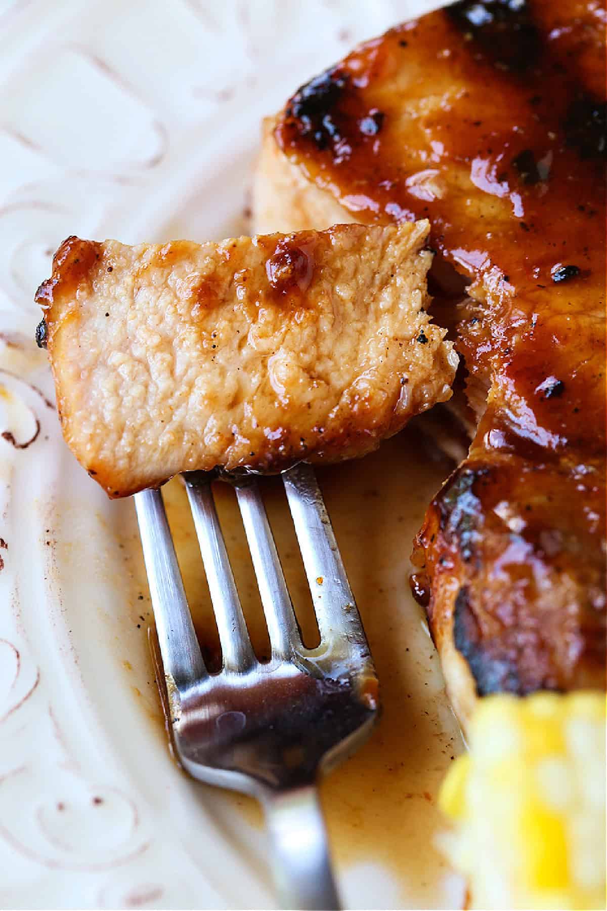 fork with piece of pork chop on white plate