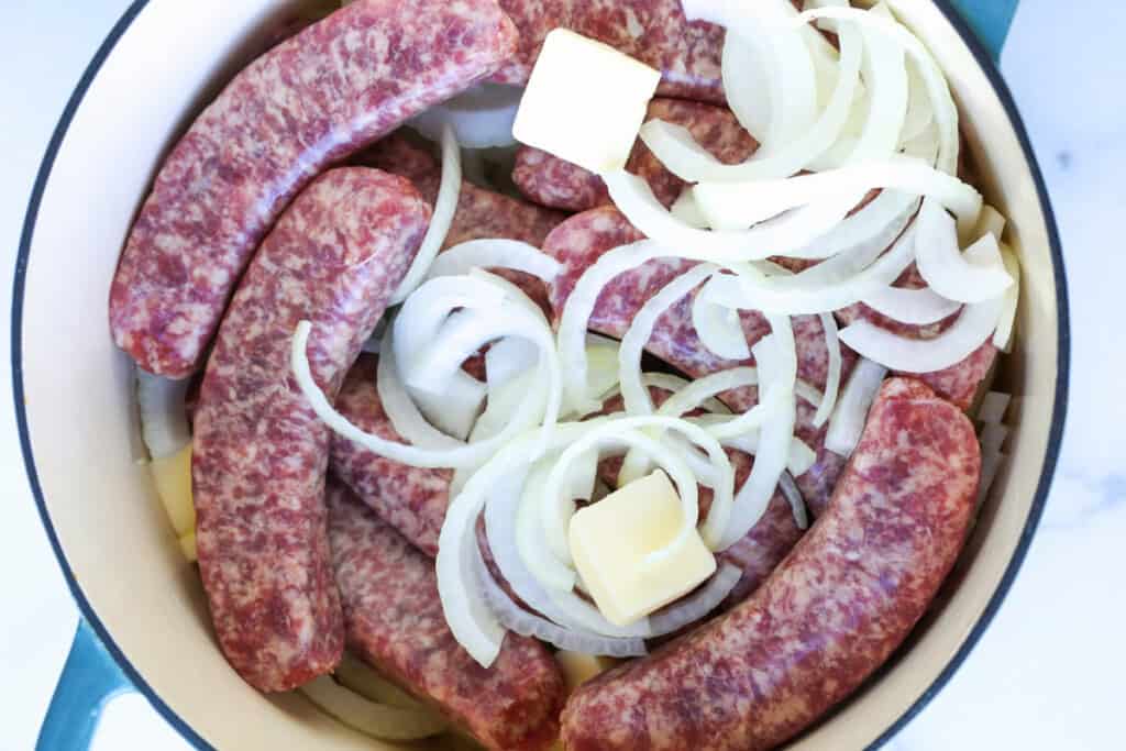 raw bratwurst with onions and butter in pot