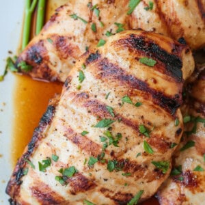 close up of grilled chicken breasts on platter with juice