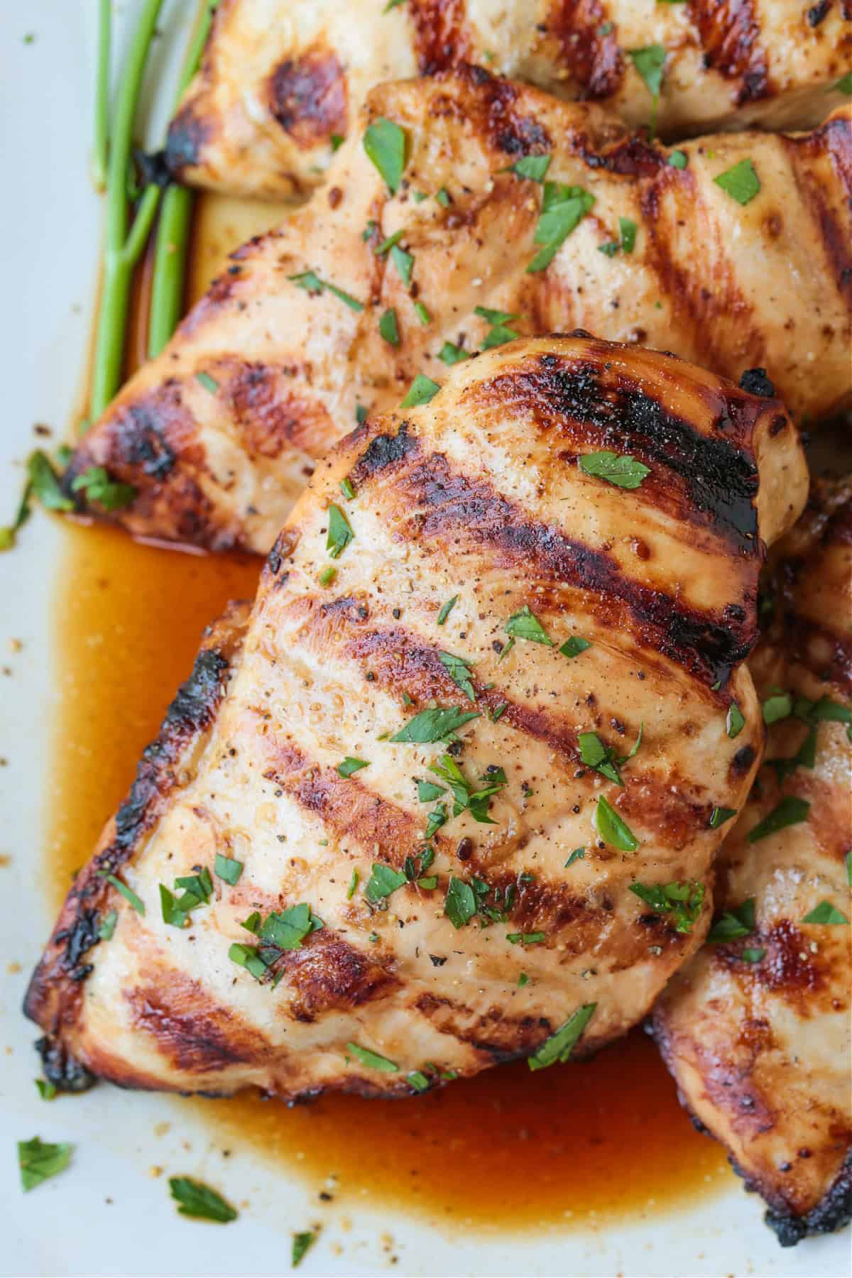 close up of grilled chicken breasts on platter with juice
