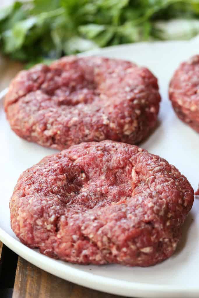 raw hamburger patty with indent on plate