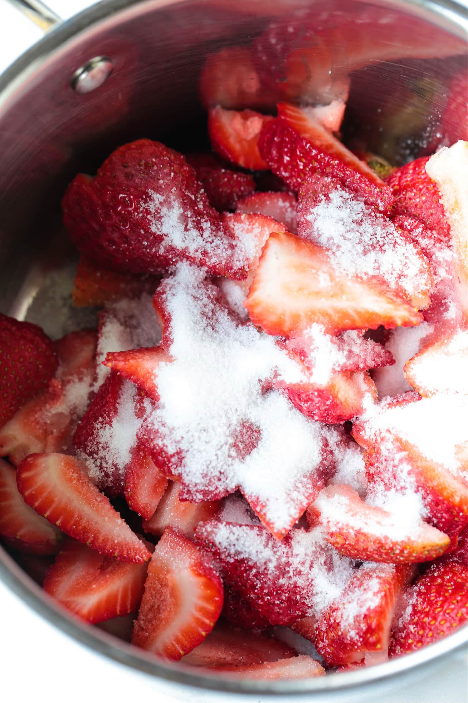cut strawberries in a pot with sugar