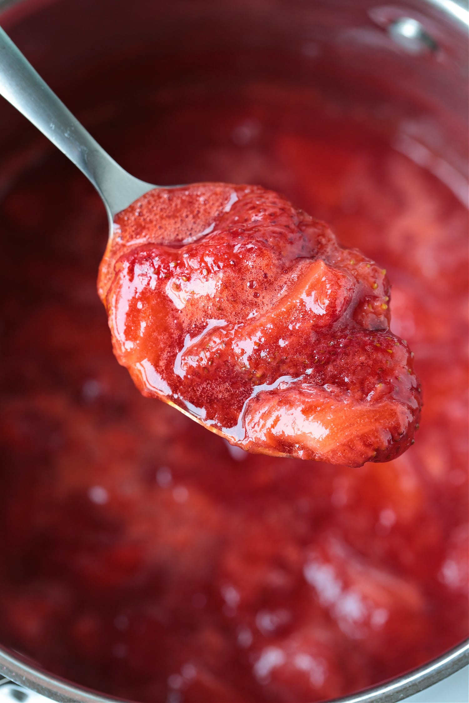 strawberry compote on a spoon over a pot