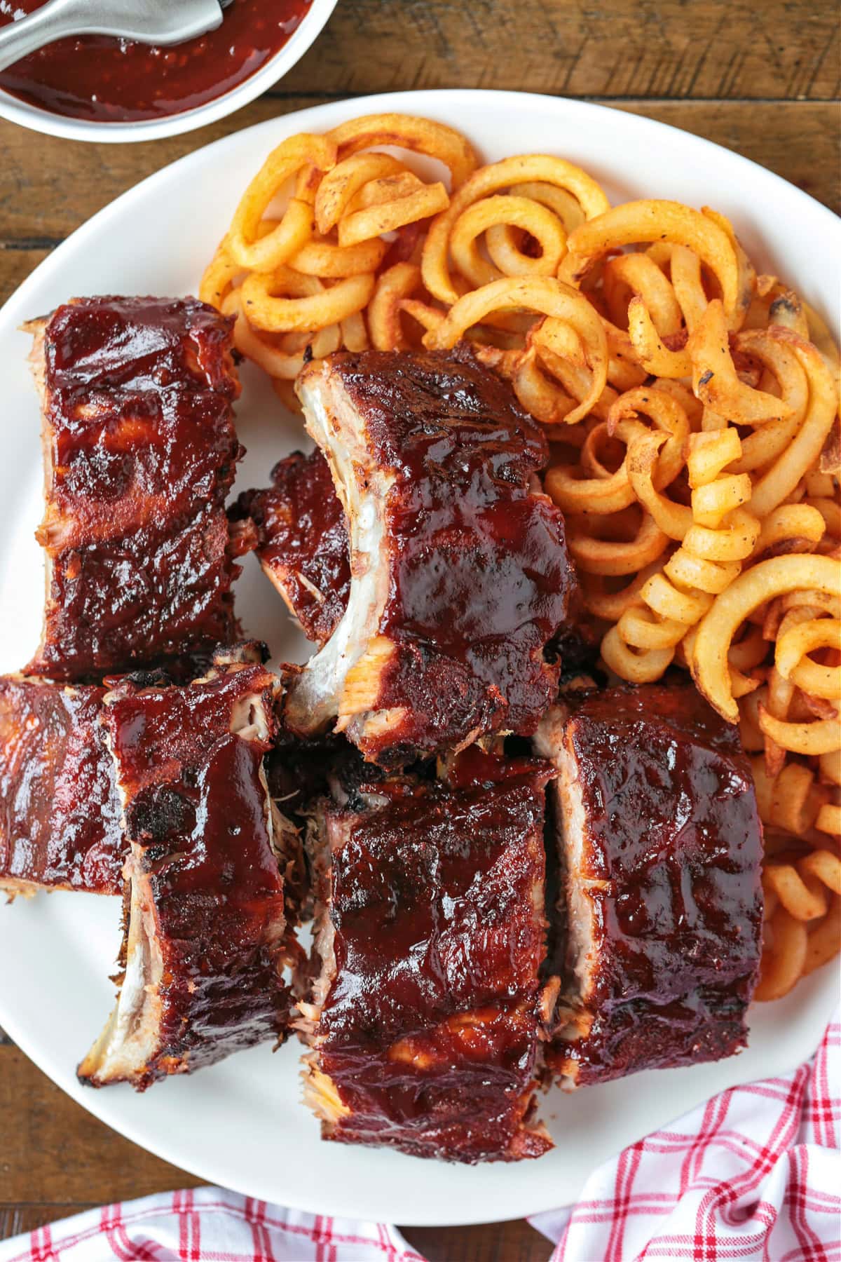 sections of bbq ribs on plate with curly fries