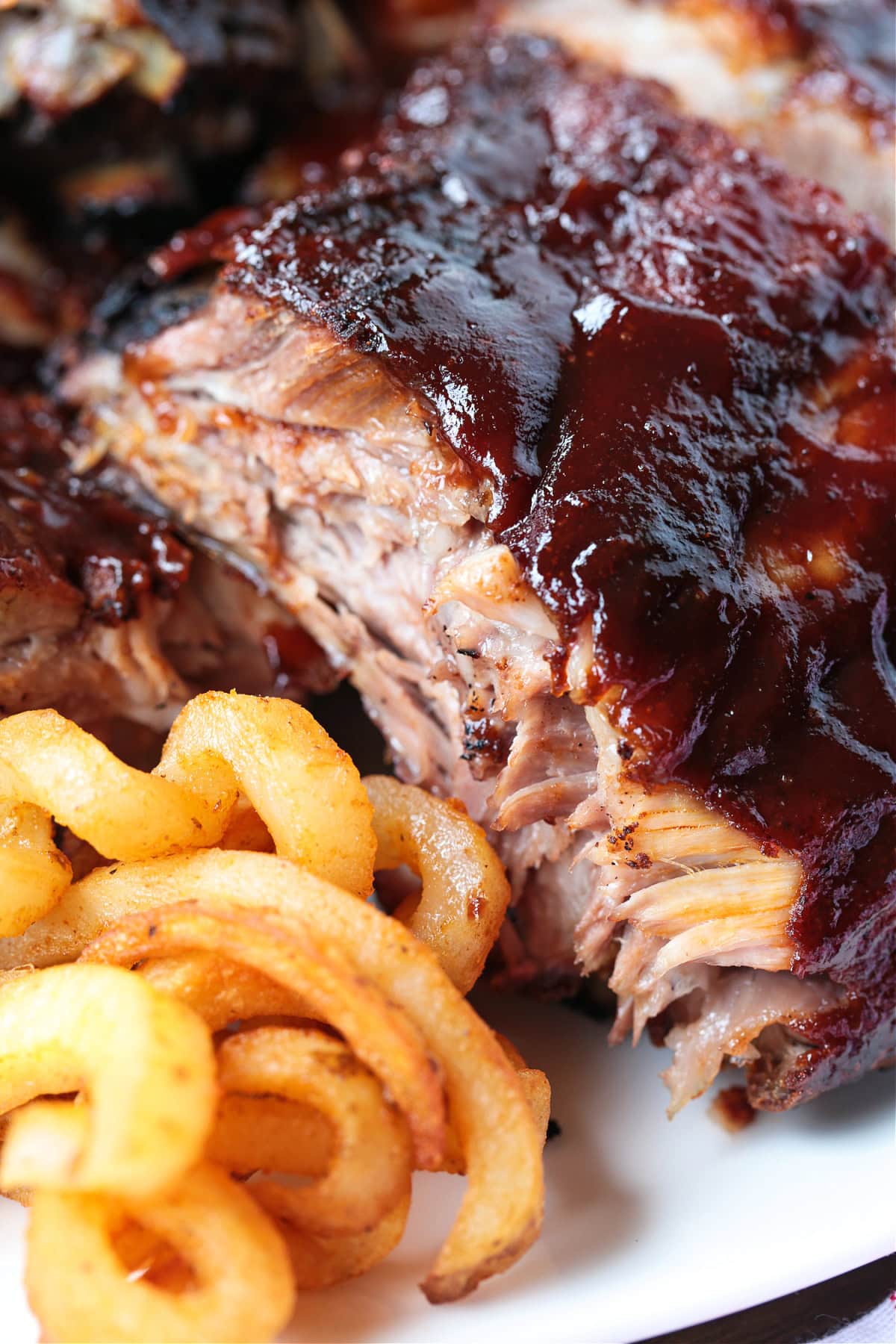 bbq ribs stacked on a plate with curly fries
