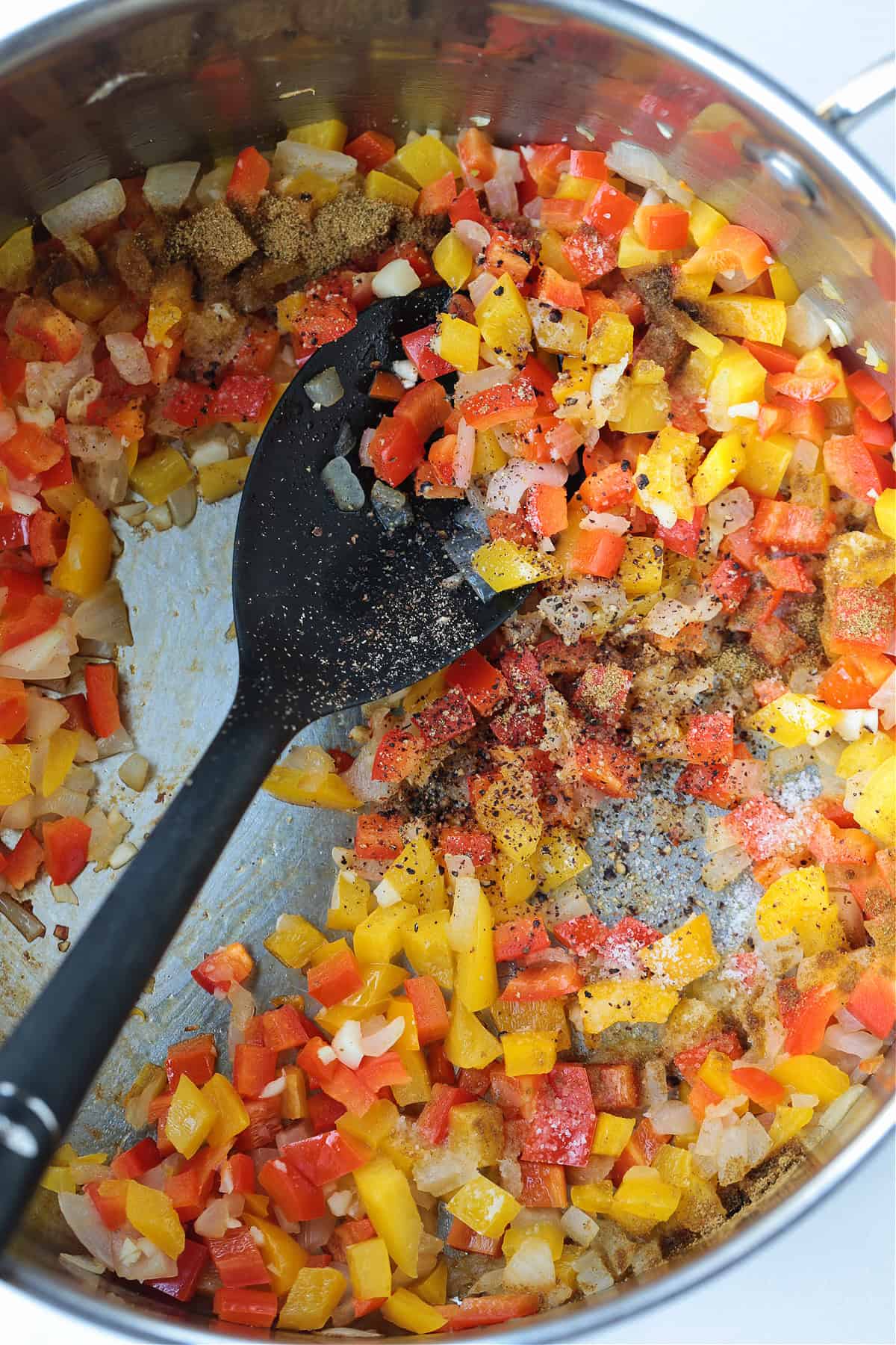 peppers and onions cooking in a pot with spoon