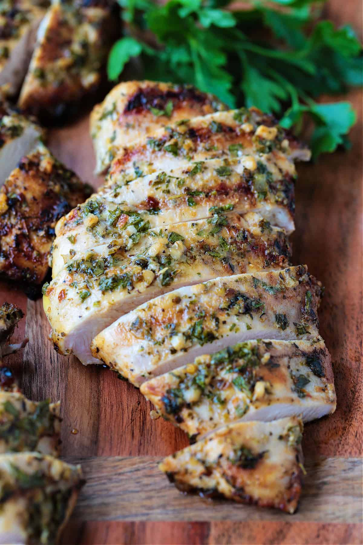 grilled chicken breast sliced on board with parsley