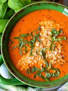 tomato soup with fresh basil and parmesan cheese in green bowl