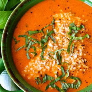 tomato soup with fresh basil and parmesan cheese in green bowl