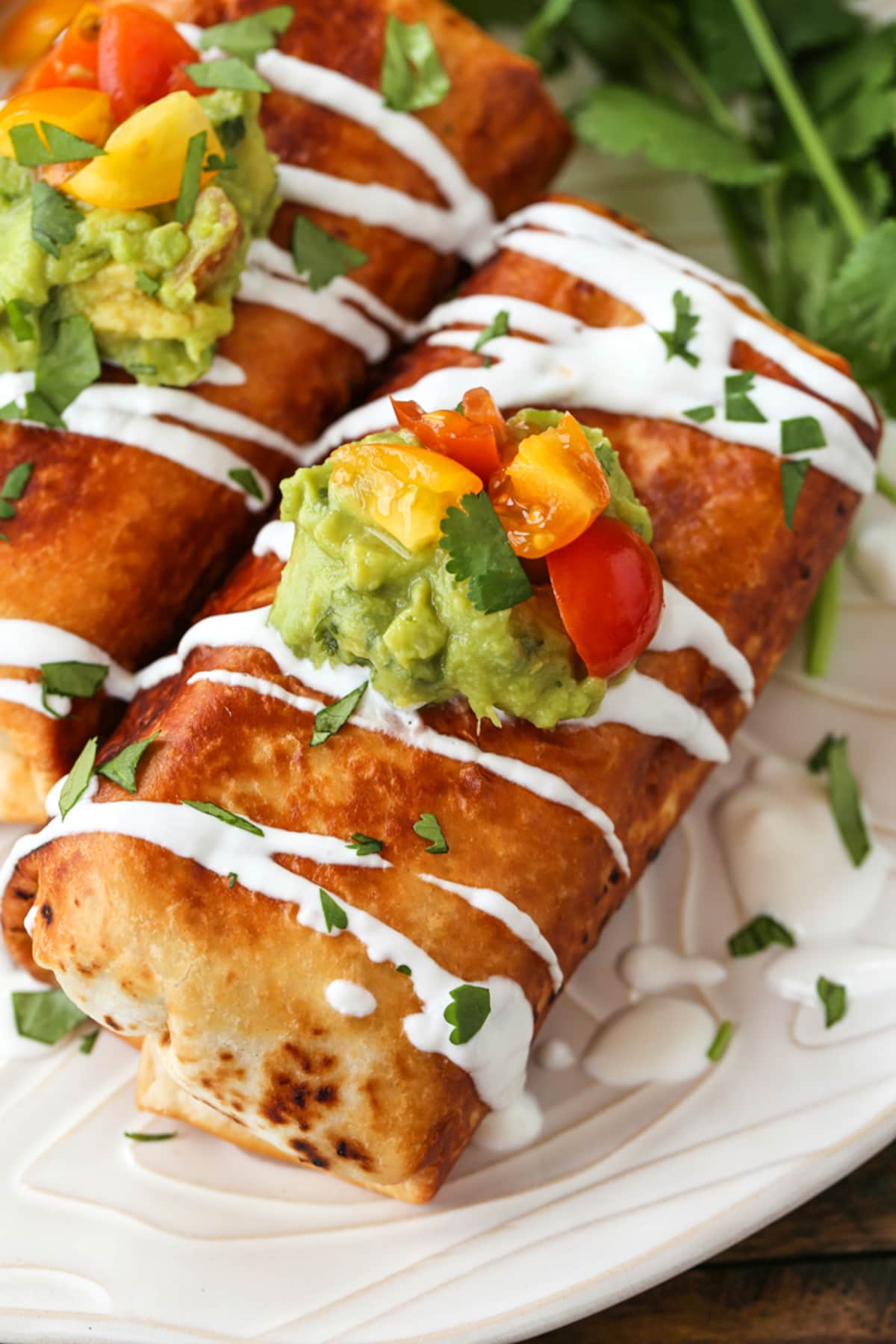 Chicken Chimichangas on a plate with sour cream drizzle