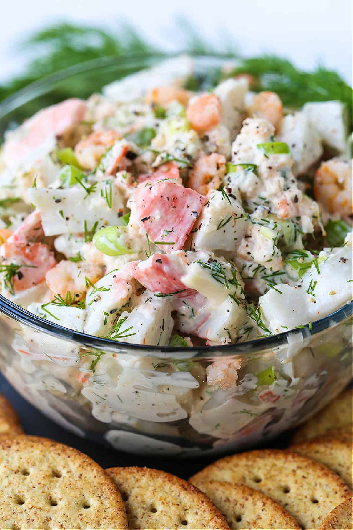bowl of cold seafood salad with fresh dill garnish