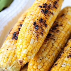 grilled corn on the cob on a white platter