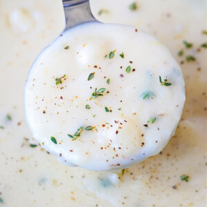 a ladle of potato soup with thyme and fresh pepper