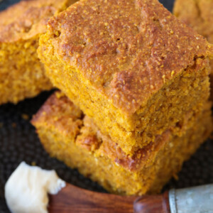 pumpkin cornbread stacked on plate with butter